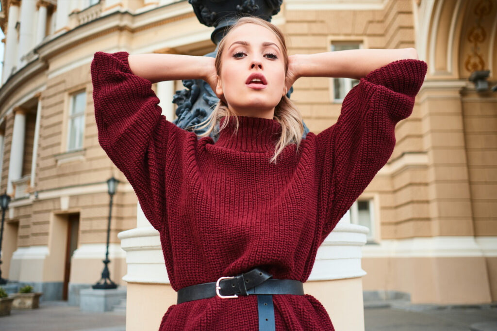 portrait of attractive blond girl in knitted sweater sensually looking in camera outdoor